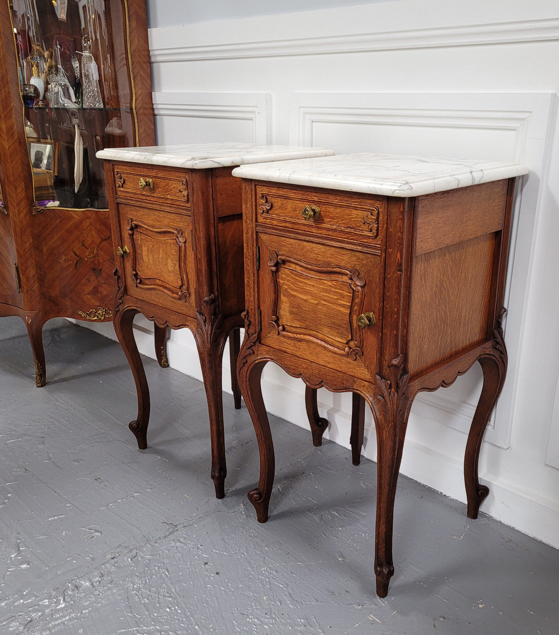 Pair of French Antique Louis XV style Oak marble top night stands. They have beautiful carved cabriole legs and beautiful white marble along with a drawer and cupboard for storage space. They have been sourced from France and are in good original detailed condition.