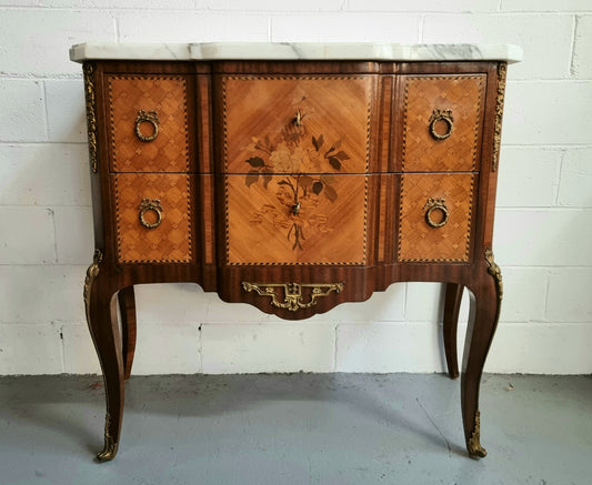 Lovely French Louis XV/XVI style Transitional marquetry inlaid commode. There are two drawers and beautiful ormolu mounts with a nice marble top in good original detailed condition.