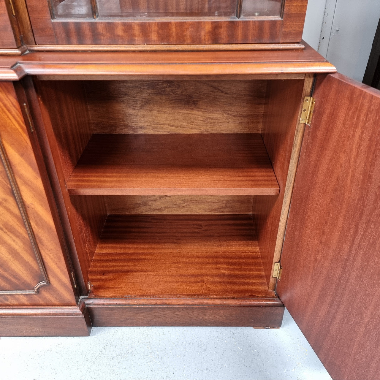 Georgian style Breakfront Flame Mahogany four door bookcase. A very impressive piece with plenty of storage and is of pleasing narrow proportions. It has been sourced locally and is in good original detailed condition.