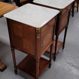 Pair of white marble topped Louis 16th style bedside cabinets consisting of one drawer and one cupboard.  Inlaid with burr walnut and has decorative mounts. They have been sourced from France and are in good original condition.
