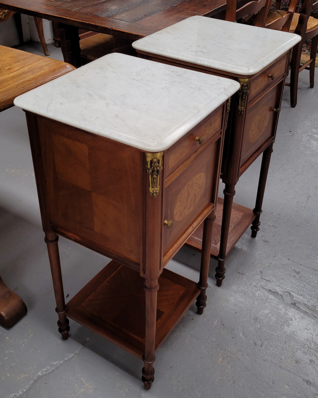 Pair of white marble topped Louis 16th style bedside cabinets consisting of one drawer and one cupboard.  Inlaid with burr walnut and has decorative mounts. They have been sourced from France and are in good original condition.