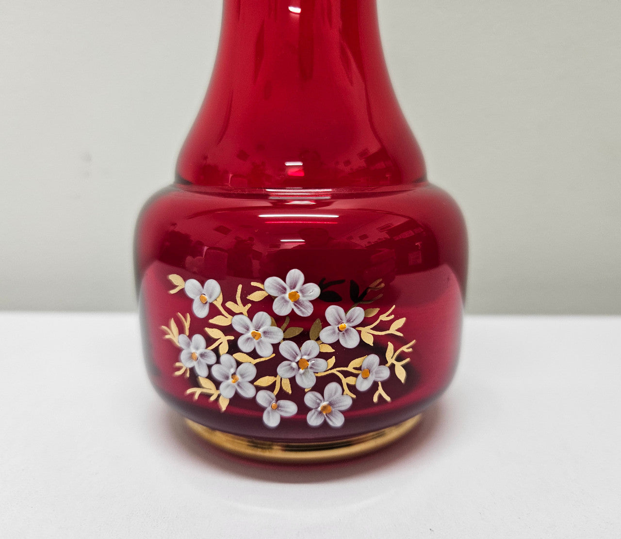 Lovely Bohemian ruby red glass vase with hand painted flowers and a guilt trimmings. It is in good original condition. Please see photos as they form part of the description.