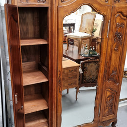 French Walnut Louis XV style three door armoire with 10 fully adjustable shelves in total spread over three sections, two drawers and a mirrored middle door. It has been sourced from France and in good original detailed condition.