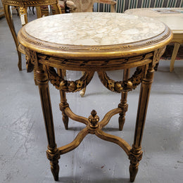 French Louis XVI style round marble topped gilded lamp/side table featuring lovely carved swags and undercarriage. It has been sourced from France and is in good original detailed condition.