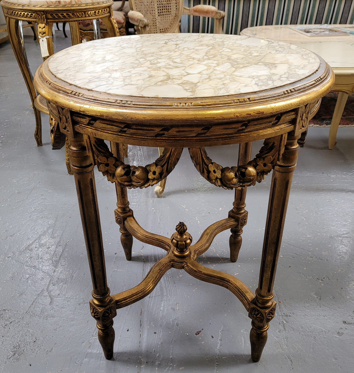 French Louis XVI style round marble topped gilded lamp/side table featuring lovely carved swags and undercarriage. It has been sourced from France and is in good original detailed condition.
