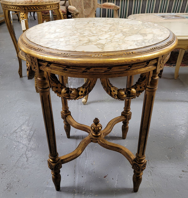 French Louis XVI style round marble topped gilded lamp/side table featuring lovely carved swags and undercarriage. It has been sourced from France and is in good original detailed condition.