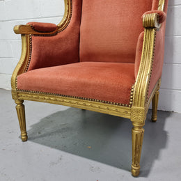 Antique Louis XVI style gilt upholstered bergere wingback chair. The fabric is in good used condition and the chair is very comfortable to sit in.