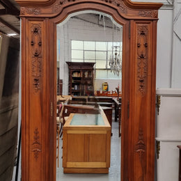 Imposing Louis XV style single mirrored door Walnut armoire. Features deep carved decoration, two interior drawers and three adjustable shelves. It is in good original detailed condition and has been sourced from France.