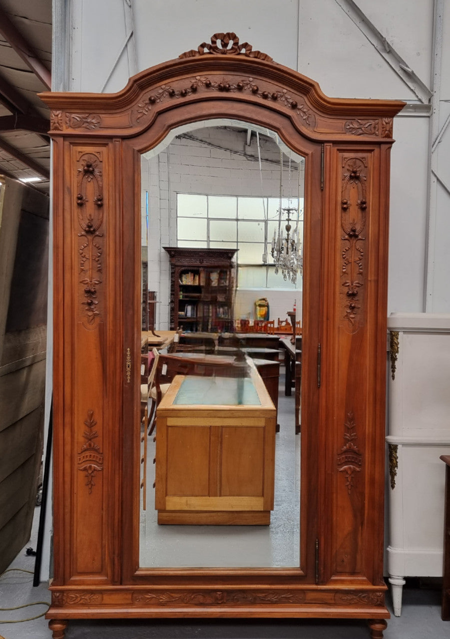 Imposing Louis XV style single mirrored door Walnut armoire. Features deep carved decoration, two interior drawers and three adjustable shelves. It is in good original detailed condition and has been sourced from France.