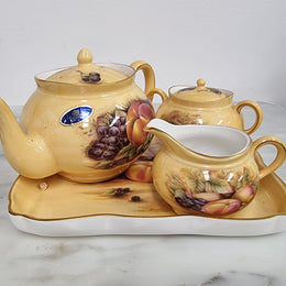 “Aynsley Orchard Gold” tea set on tray. Consisting of small teapot, lidded sugar and creamer. Please view photos as they help form part of the description.