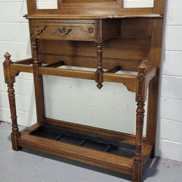 Impressive Oak hall stand of grand portions. Plenty of storage with a drawer, plenty of hooks and two sections for umbrealls/ walking sticks. It is in good original detailed condition.
