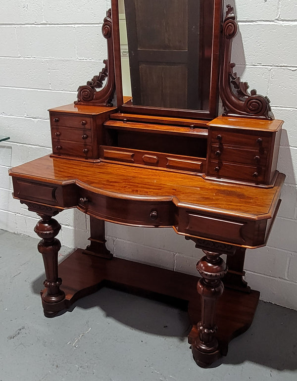 Beautiful Flame Mahogany Victorian duchess dressing table. Circa 1880 in date. It has a serpentine front outline and has an adjustable swing frame mirror. It is fitted with a central roll up storage section and then has three small drawers to either side, aswell as a central drawer in the middle of the serpentine front. It is in good original condition.
