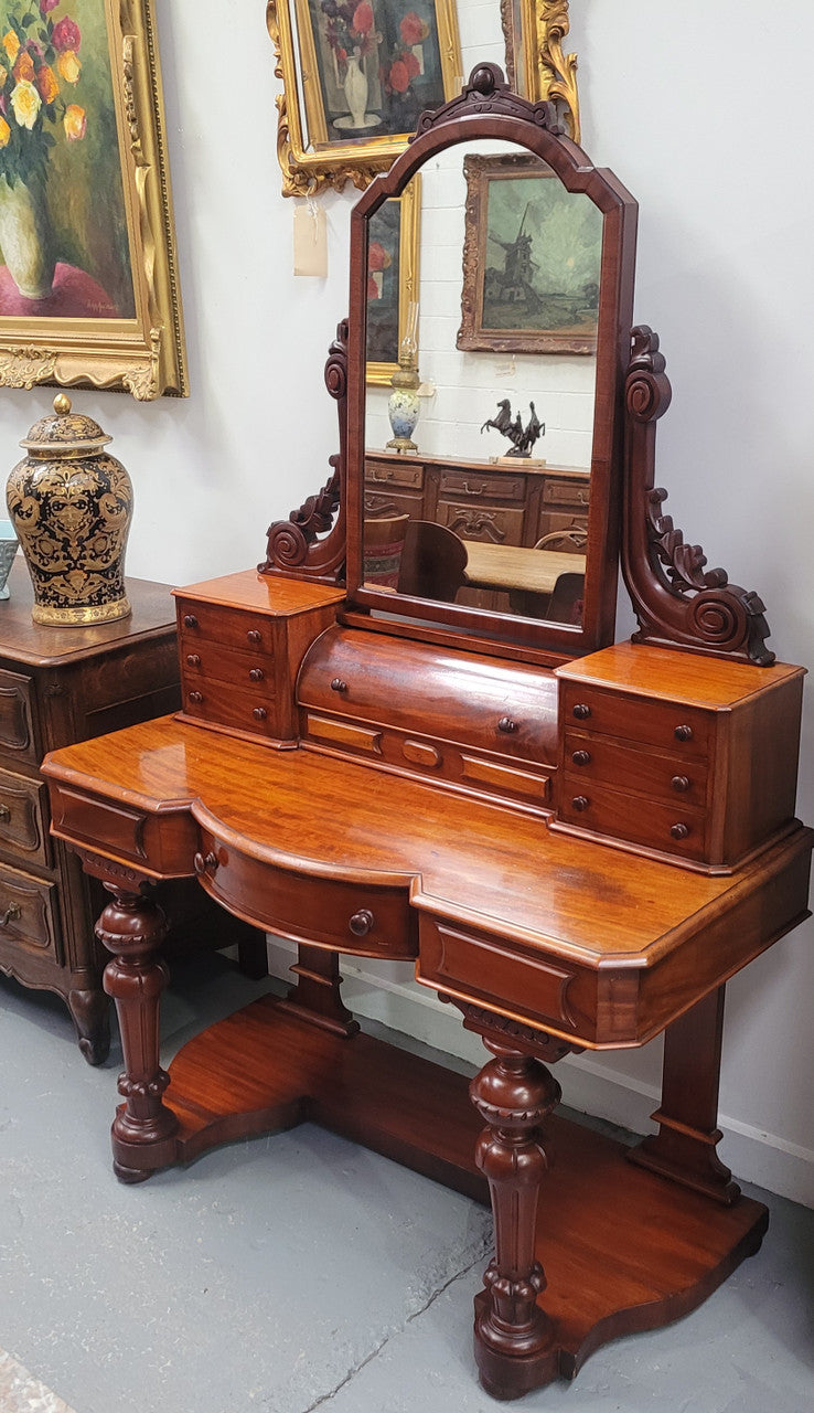 Beautiful Flame Mahogany Victorian duchess dressing table. Circa 1880 in date. It has a serpentine front outline and has an adjustable swing frame mirror. It is fitted with a central roll up storage section and then has three small drawers to either side, aswell as a central drawer in the middle of the serpentine front. It is in good original condition.