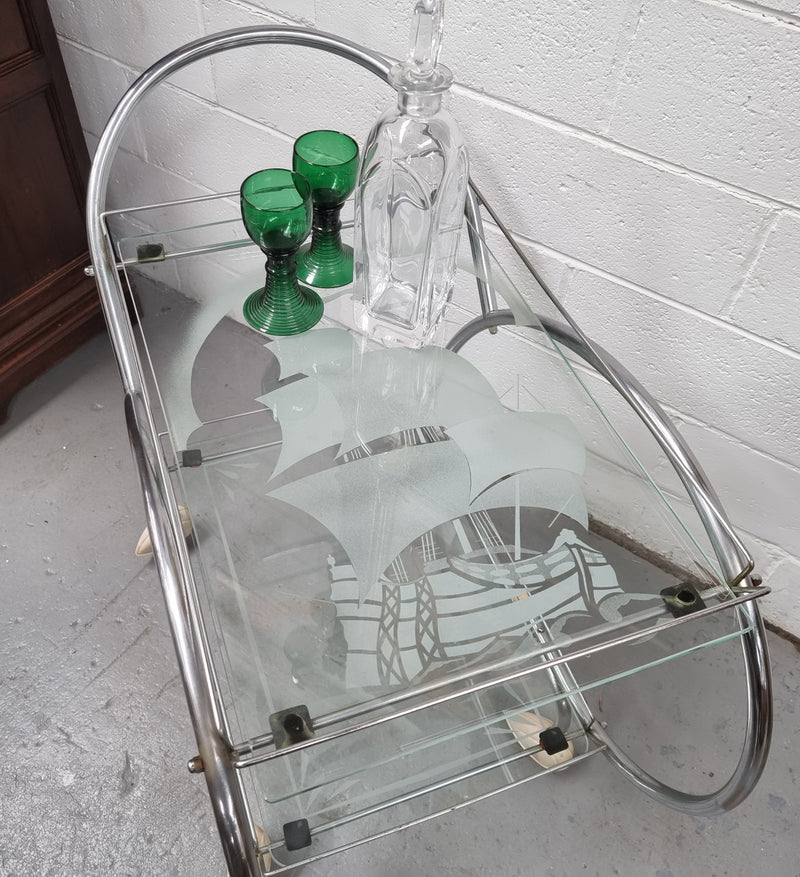 Stylish Art Deco chrome & frosted glass drinks trolley. Bakelite guards on the wheels. It is in good original condition and has been sourced locally.