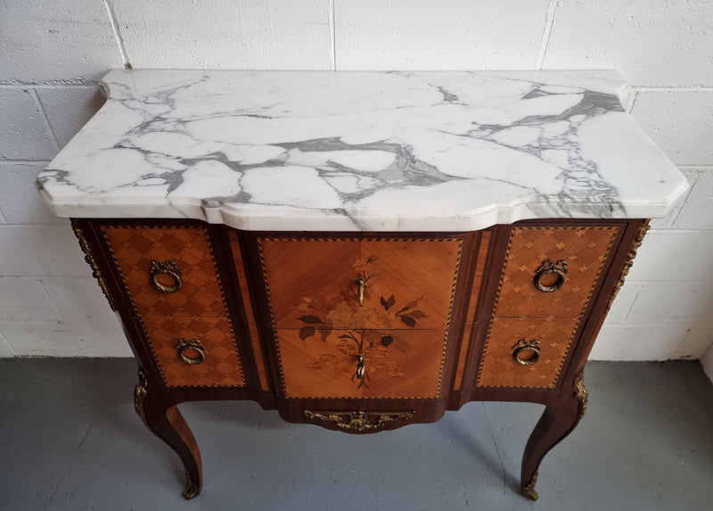 Lovely French Louis XV/XVI style Transitional marquetry inlaid commode. There are two drawers and beautiful ormolu mounts with a nice marble top in good original detailed condition.
