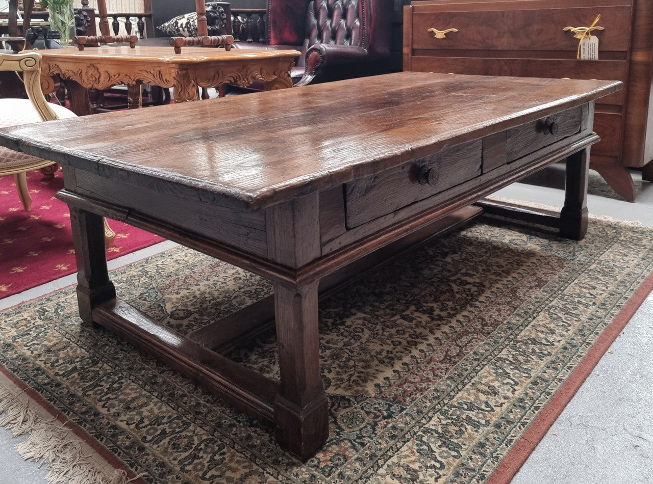 Impressive large size rustic French Oak coffee table with two drawers on a stretcher base. In good original detailed condition and sourced from France.