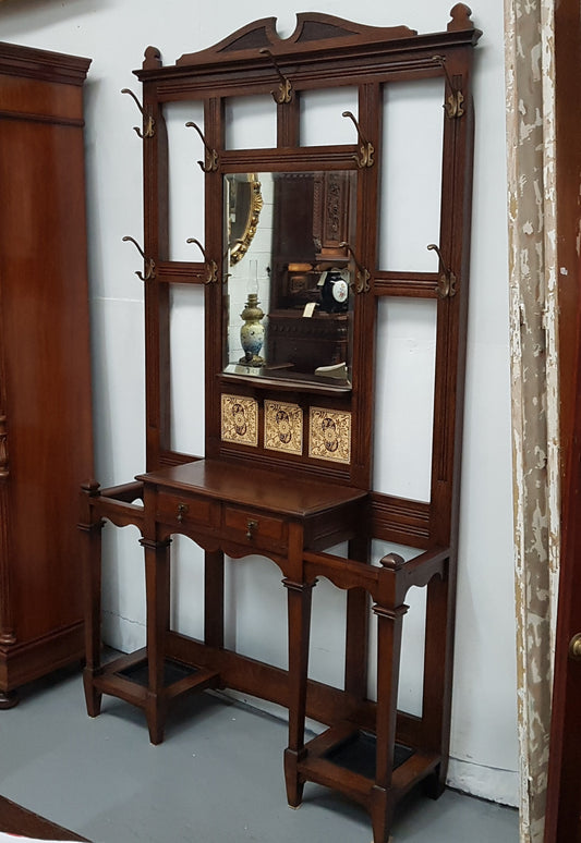 Beautiful English Edwardian tiled back hall stand, with nine brass hooks, two small drawers and retaining it's original mirror and showing signs of age. In good original condition.