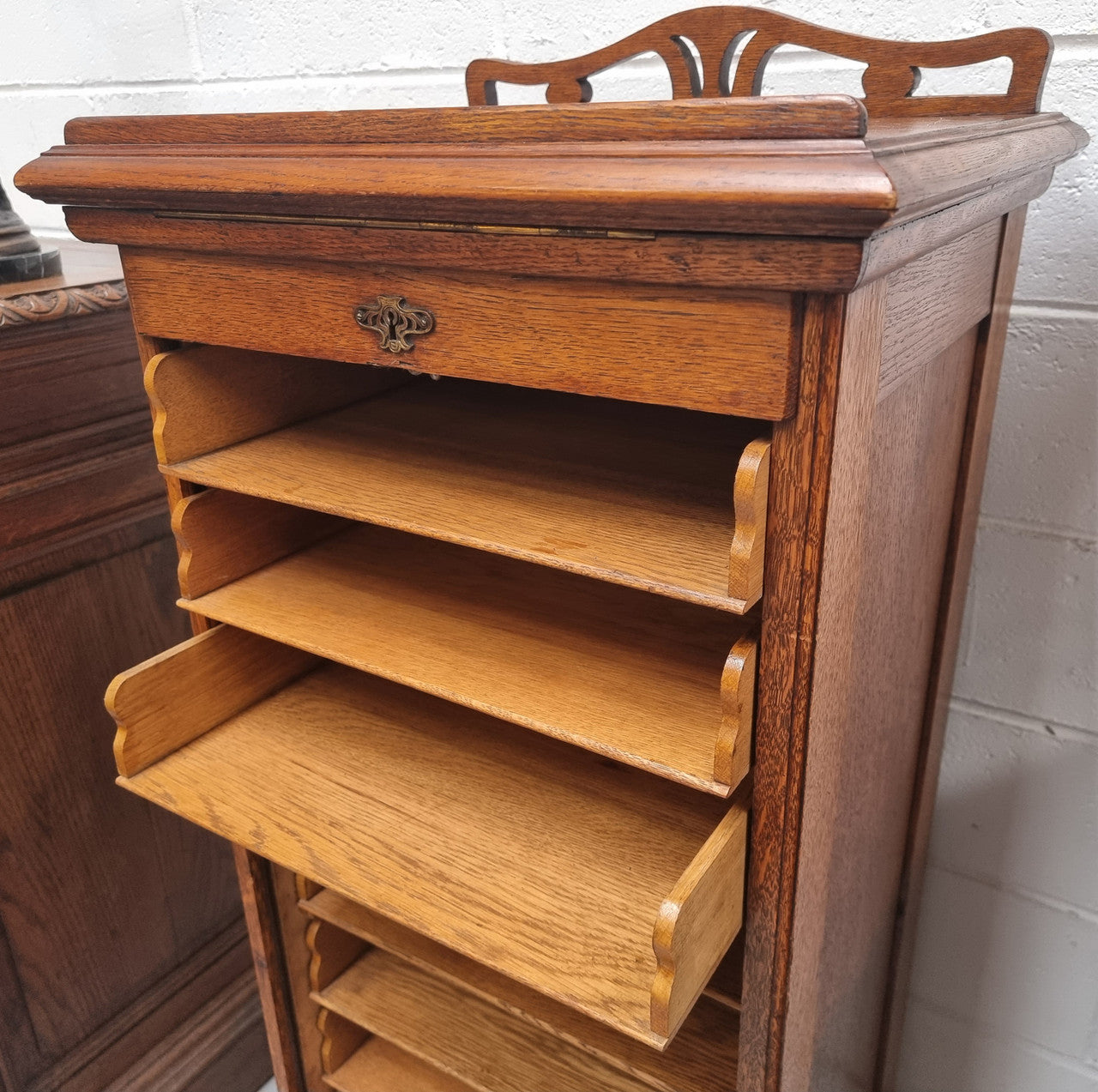 Antique Edwardian roll top Tambour file cabinet desk. This practical antique tambour front filing cabinet dates around 1900 in the Edwardian period and is constructed from Oak. This antique cabinet has an adjustable writing slope, above a tambour front with key and working lock. It has been sourced locally and is in good original detailed condition.