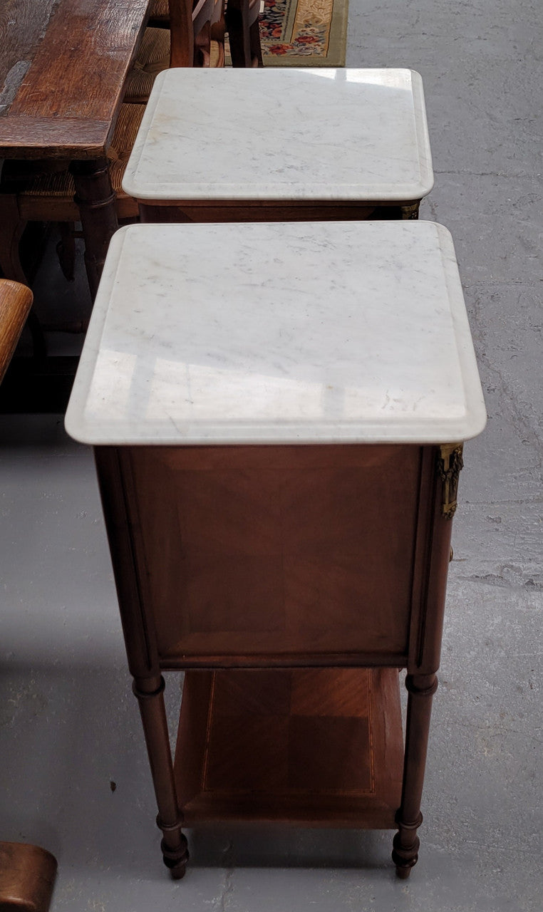 Pair of white marble topped Louis 16th style bedside cabinets consisting of one drawer and one cupboard.  Inlaid with burr walnut and has decorative mounts. They have been sourced from France and are in good original condition.