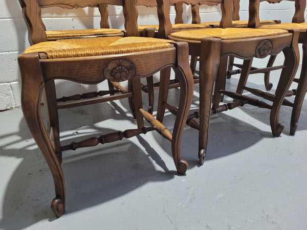 A set of 6 French Louis XV style oak dining chairs with rush seats in good original condition. All chairs have been detailed and re-glued where needed.