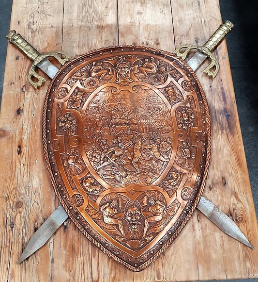 A beautiful European Antique very detailed embossed copper Shield with Swords. Look closely to see the amazing detail in the shield of a fighting scene. It has brass handles on the steel swords. It is In amazing original condition.