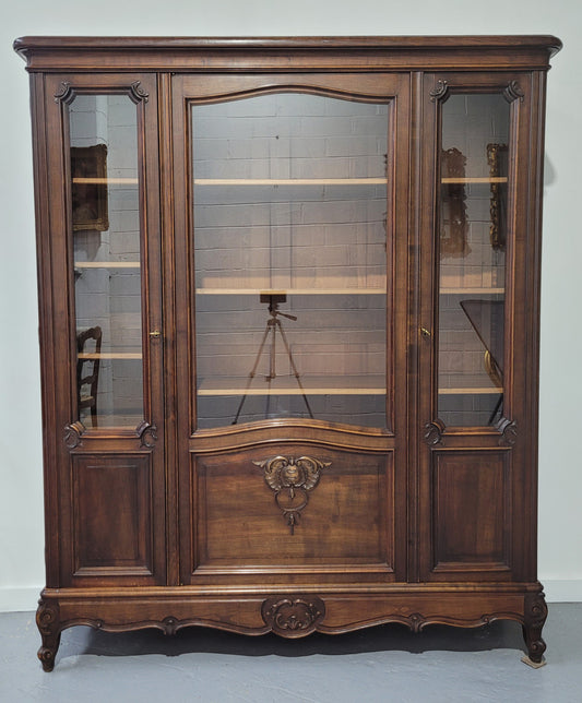 French Louis XV style walnut three door bookcase. It has adjustable shelves and is in good original detailed condition.