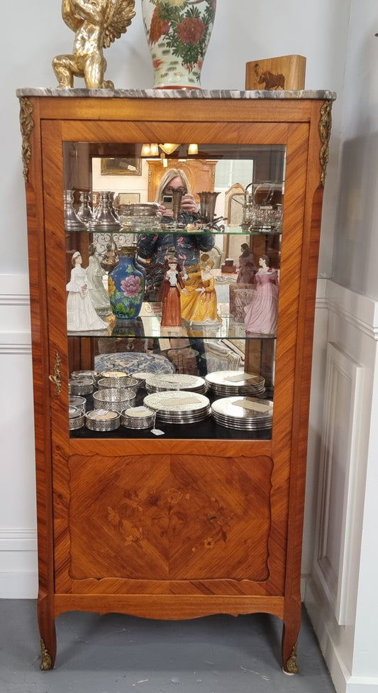 Beautiful French walnut inlaid vitrine with a lovely marquetry design and ormolu mounts. Has a beautiful coloured marble top and two glass shelves. In good original condition.