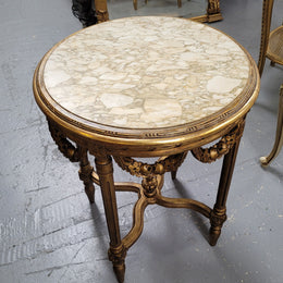 French Louis XVI style round marble topped gilded lamp/side table featuring lovely carved swags and undercarriage. It has been sourced from France and is in good original detailed condition.