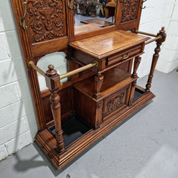 Grand Henry 2nd Style French Oak hall stand with 12 hanging hooks. Also has one cupboard and drawer for storage along with a mirror and two areas either side for umbrellas and walking sticks. In good original detailed condition.