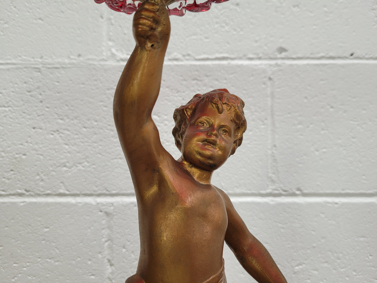 Late Victorian spelter table centerpiece/comfort featuring putti holding ruby glass bowl. In good original condition with no damage to the glass.