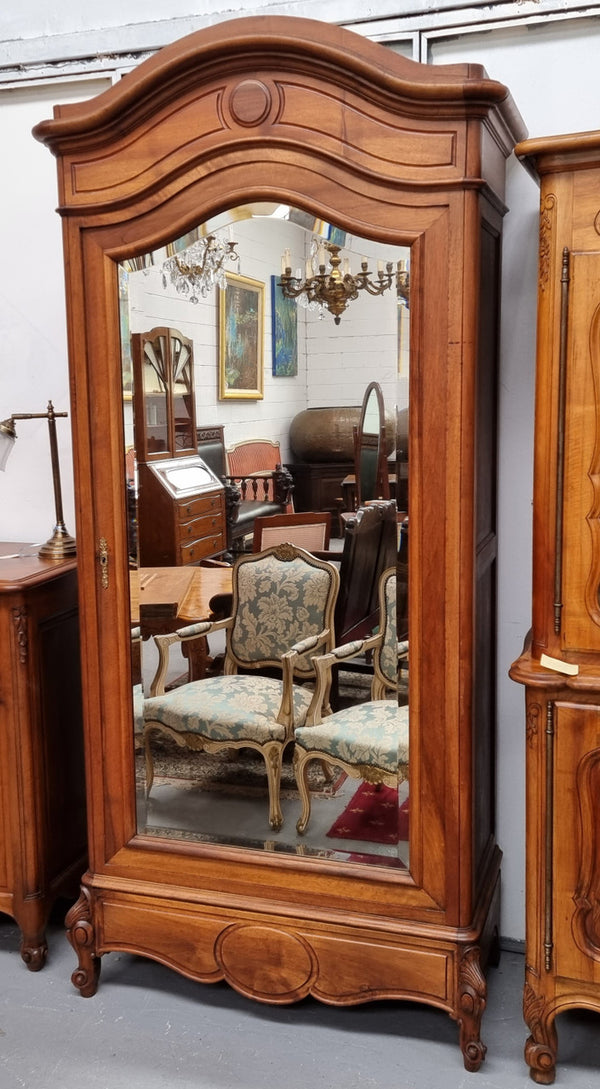 French Louis XV style Walnut armoire with single bevelled mirrored door. It has four adjustable shelves and a hidden exterior drawer at the bottom. It has been sourced from France and is in good original detailed condition.