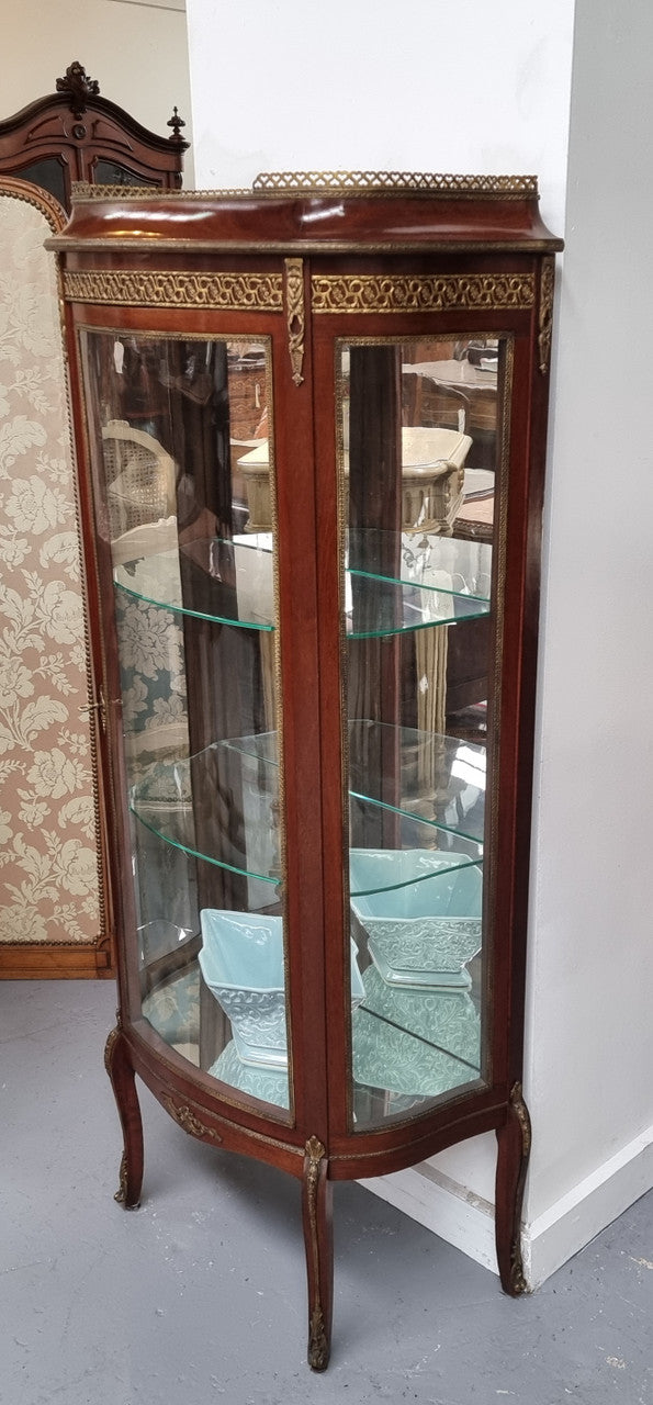 Beautiful French Louis XV style vitrine/ display cabinet with curved glass, gilt mounts, mirrored back and two glass shelves for your displays . It is in good original detailed condition.