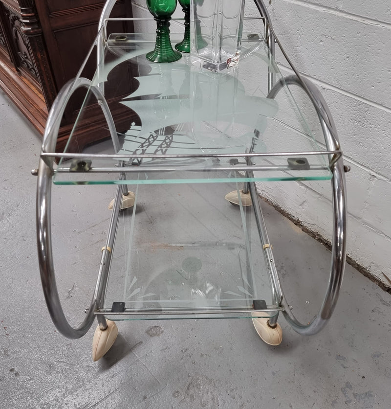 Stylish Art Deco chrome & frosted glass drinks trolley. Bakelite guards on the wheels. It is in good original condition and has been sourced locally.