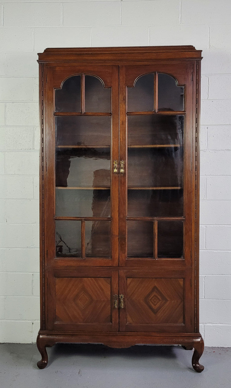 English Walnut two door bookcase with original glass. It has three adjustable shelves and hidden storage below behind two smaller doors. It is in food original condition.