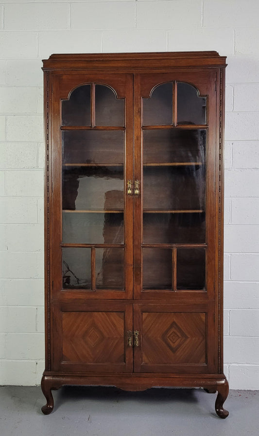 English Walnut two door bookcase with original glass. It has three adjustable shelves and hidden storage below behind two smaller doors. It is in food original condition.