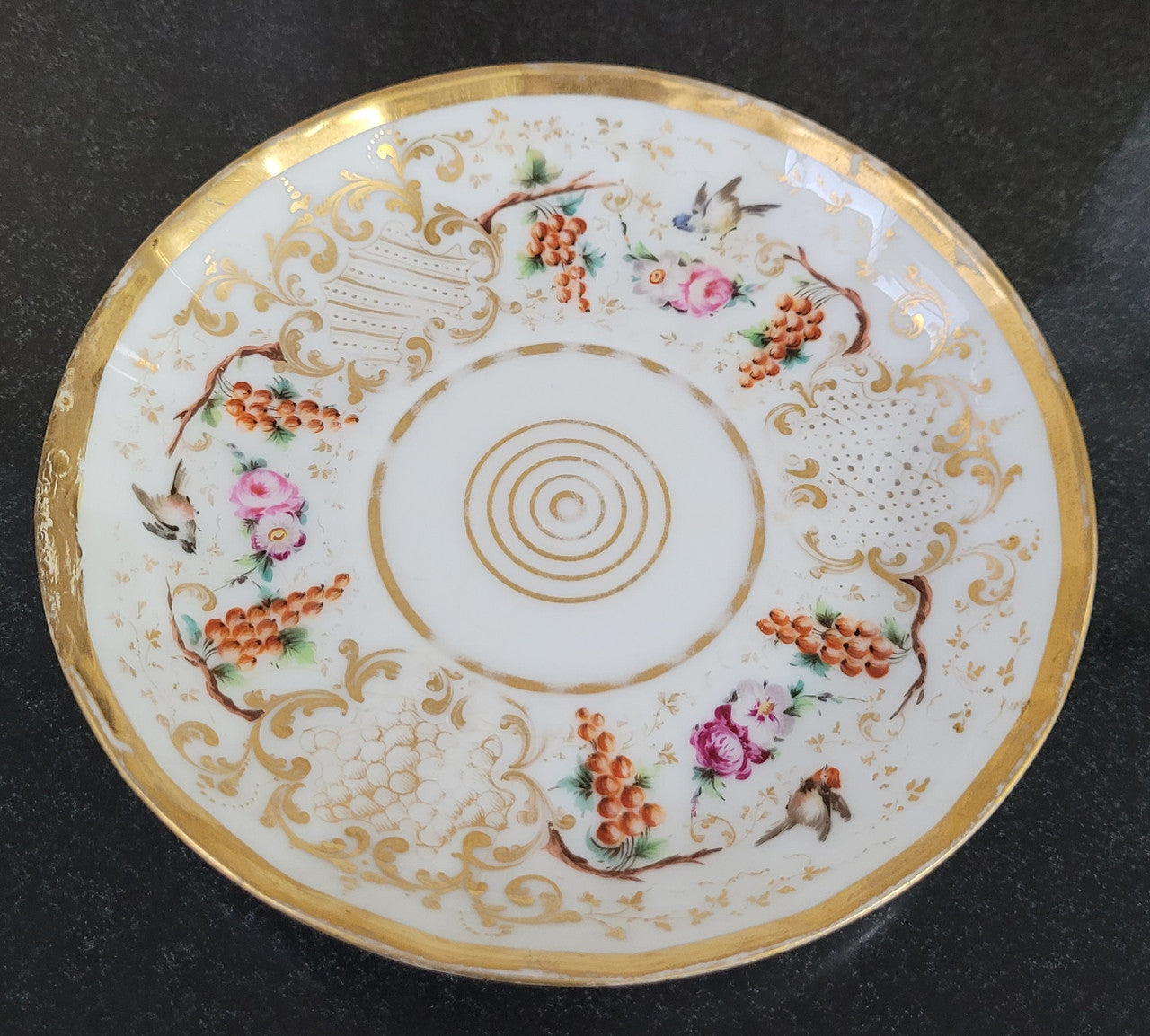 “Old Paris Porcelain” large cup and saucer, beautifully decorated with birds, grapes, floral sprays and heavily gilded. Dated to base 1835. In good original condition please view photos as they help form part of description.