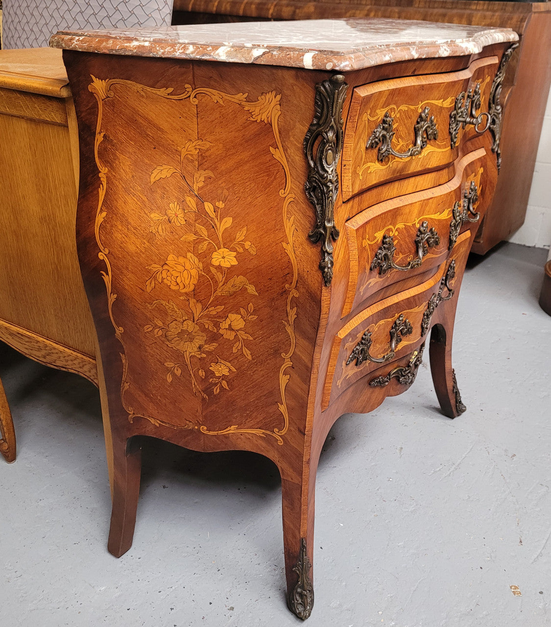 Antique French Louis XV style compact three drawer marble top commode with marquetry inlay and ormolu mounts. Sourced from France and in good original detailed condition.