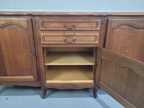 French Louis XV style parquetry top three door sideboard with two drawers. Plenty of storage space with a shelf behind each door. It is in good original detailed condition.