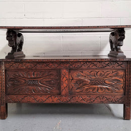 Unusual English Oak Monks Bench.  The tabletop is set onto a lift top chest in such a way that when the table is not in use, the top pivots to a vertical position and becomes the back of a Settle. Carved Lion table rests and carving to front.  In good, detailed condition.