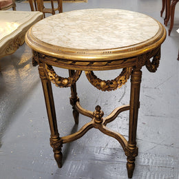 French Louis XVI style round marble topped gilded lamp/side table featuring lovely carved swags and undercarriage. It has been sourced from France and is in good original detailed condition.