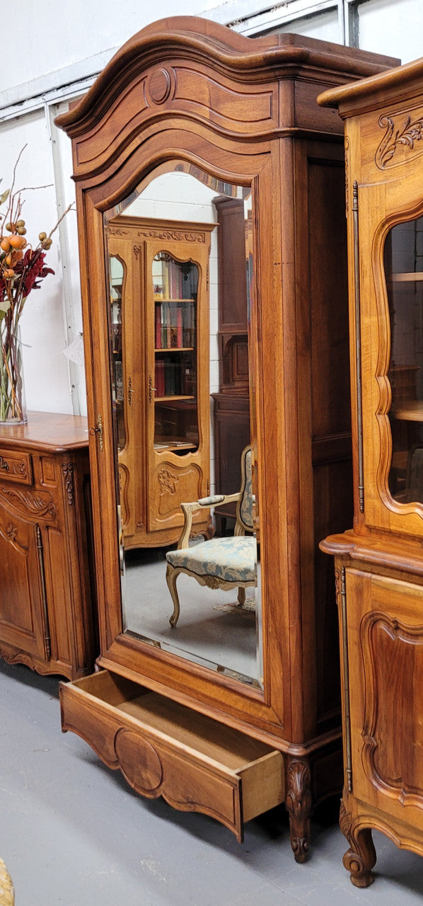 French Louis XV style Walnut armoire with single bevelled mirrored door. It has four adjustable shelves and a hidden exterior drawer at the bottom. It has been sourced from France and is in good original detailed condition.