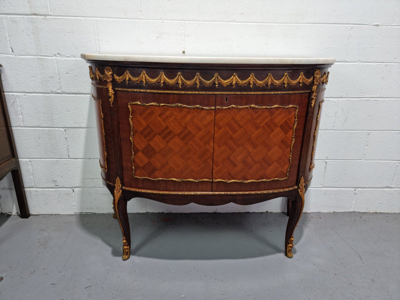 Vintage French style marble top two door half-moon buffet with beautiful decorative brass gilt mounts. In good original detailed condition.