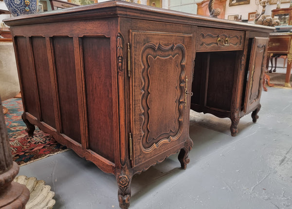 Fabulous Louis XV style French Oak beautifully carved full partners desk with an amazing tooled leather top. Both sides have a functioning drawer in the middle and two cupboards either side. On both sides one cupboard door opens up to four smaller internal drawers. Plenty of storage space and a large top surface to work on. It is in good original detailed condition.