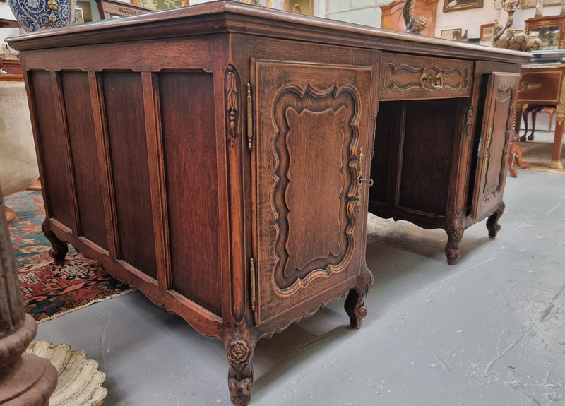 Fabulous Louis XV style French Oak beautifully carved full partners desk with an amazing tooled leather top. Both sides have a functioning drawer in the middle and two cupboards either side. On both sides one cupboard door opens up to four smaller internal drawers. Plenty of storage space and a large top surface to work on. It is in good original detailed condition.