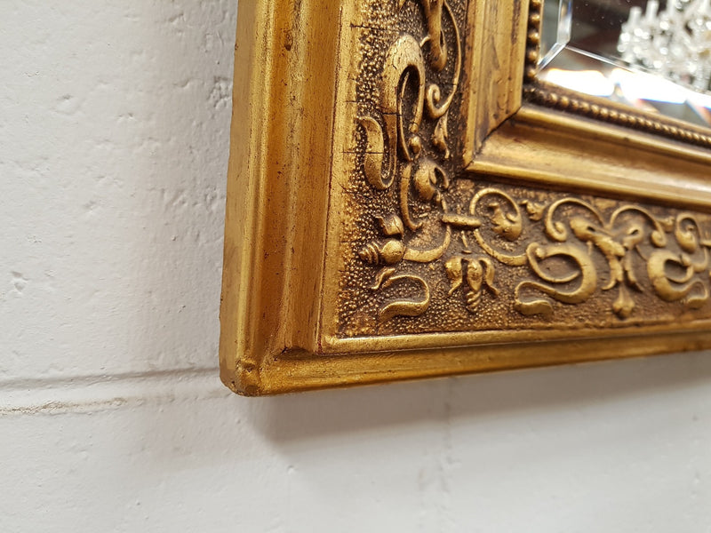 19th Century French Louis XV style gilt wall mirror with fabulous highly decorative crest at the top and a beveled edge mirror. In good original detailed condition.