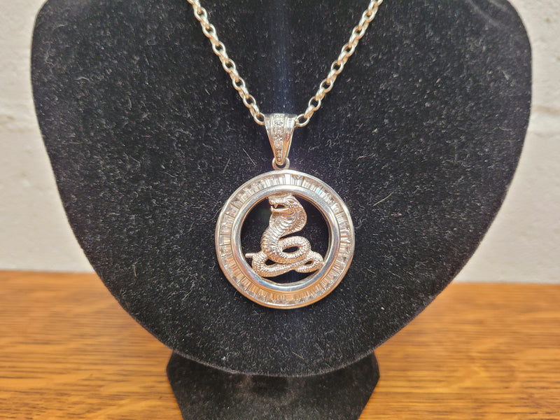 Sterling Silver pendant featuring a Cobra Snake with Cubic Zirconia surround. Heavy Bale with Cubic Zirconia. Pendant without Bale, 3.5cm Diameter. Includes 60 cm Sterling Silver Chain.