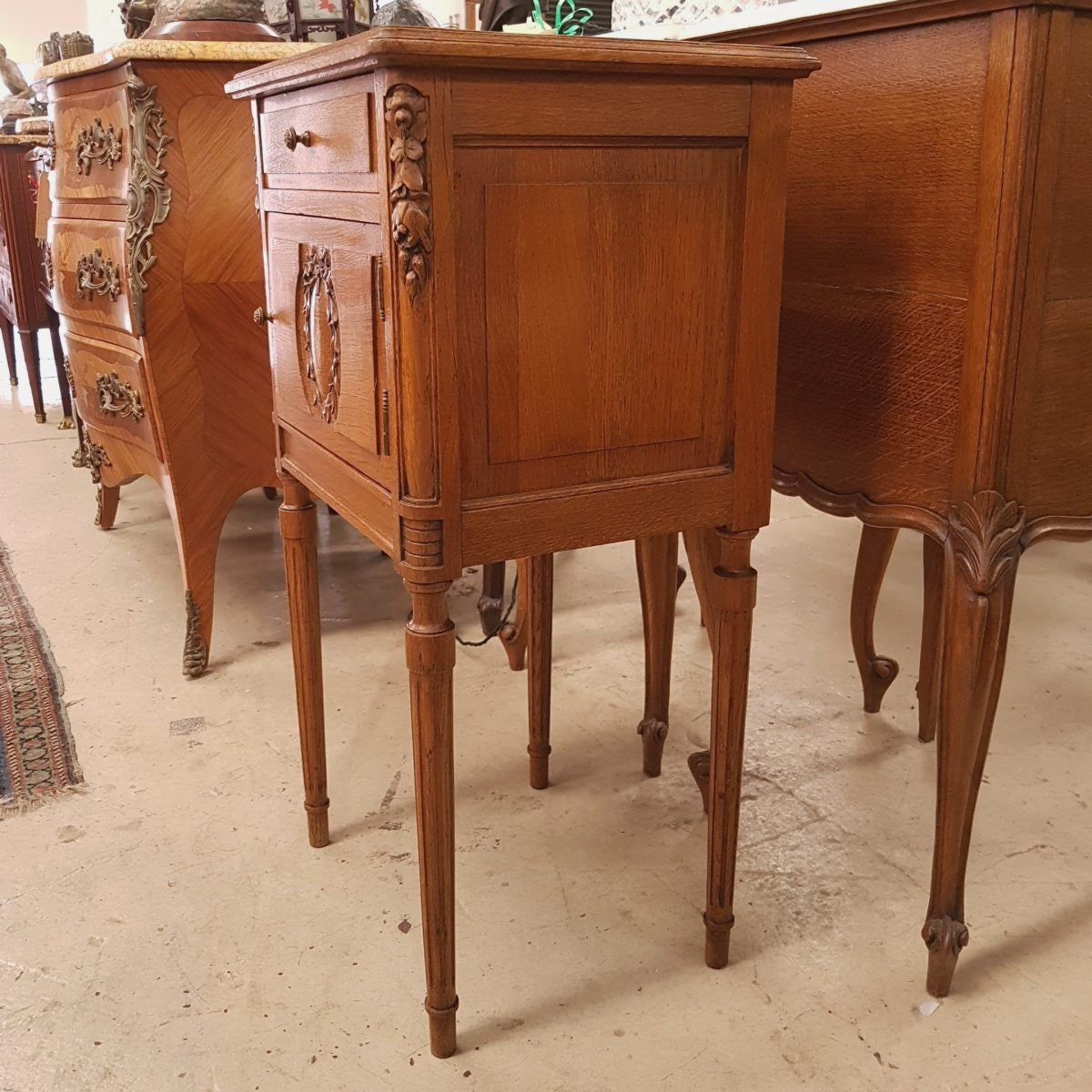A French oak single bedside cabinet, with a marble inset top, finely carved detail, cupboard space and a drawer. In good original condition.