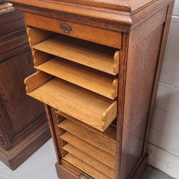 Antique Edwardian roll top Tambour file cabinet desk. This practical antique tambour front filing cabinet dates around 1900 in the Edwardian period and is constructed from Oak. This antique cabinet has an adjustable writing slope, above a tambour front with key and working lock. It has been sourced locally and is in good original detailed condition.