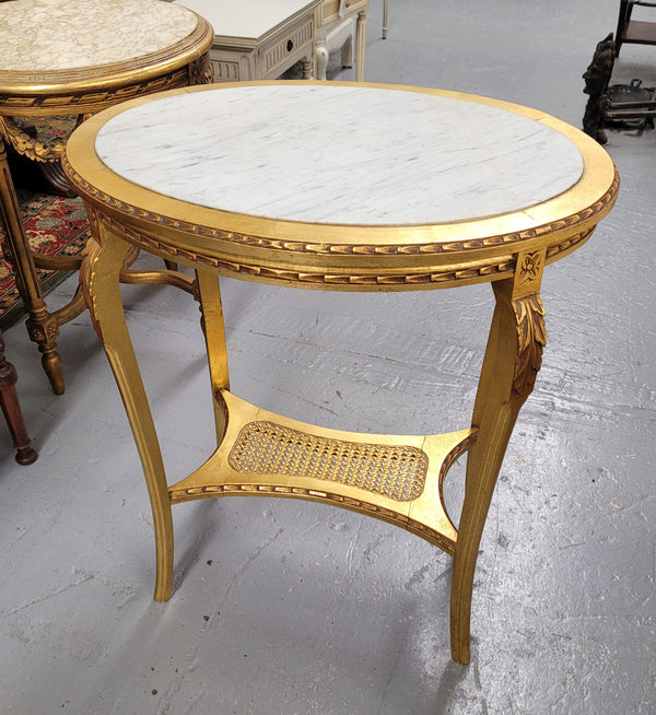 Impressive French oval Louis XVI style gilt and white marble topped two tier lamp/side table. It has been sourced from France and is in good original detailed condition.