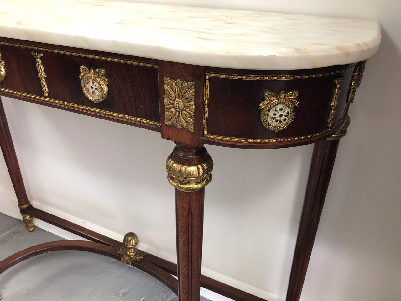 Narrow mahogany Louis XVI style console table with a marble top, ceramic inserts and gilt brass mounts.